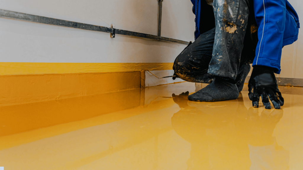 Installer applying basement floor coating in a residential setting Installer applying basement floor coating in a residential setting